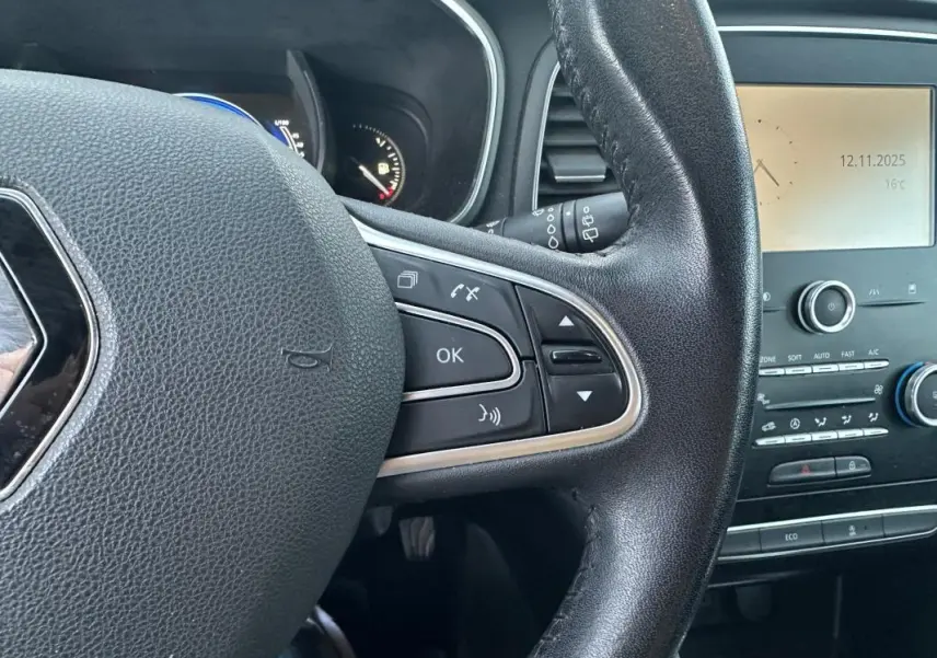 Gros plan sur le volant cuir noir de la Renault Mégane IV avec commandes multifonctions et tableau de bord partiel visible.