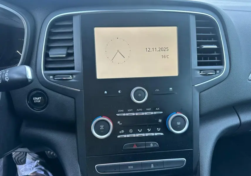 Vue rapprochée du tableau de bord noir de la Renault Mégane IV avec écran central et commandes de climatisation.