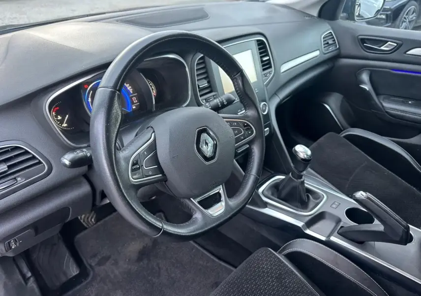 Intérieur de Renault Mégane IV TCe 130 gris foncé, vue côté conducteur sur volant cuir et levier de vitesse manuel.