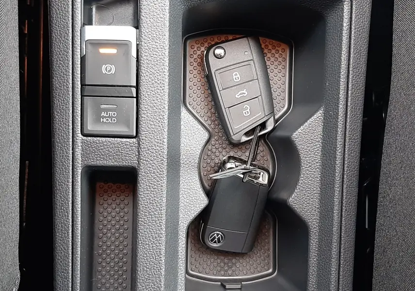 Vue plongeante sur la console centrale du Volkswagen T-Roc 2025, avec clé et bouton frein à main électronique allumé.