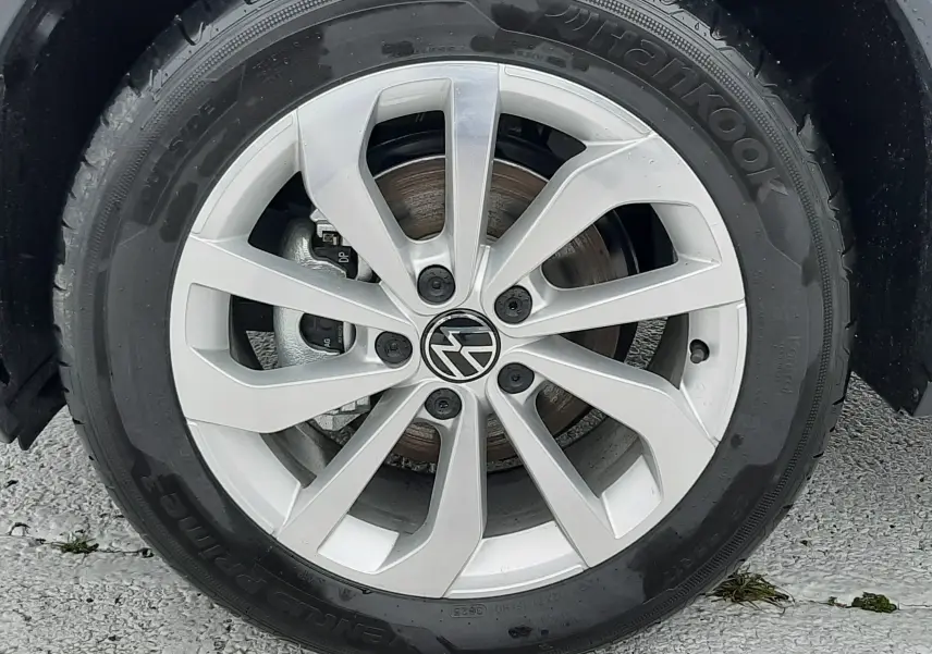Gros plan sur la jante alliage argentée avec logo Volkswagen, pneu Hankook monté sur Volkswagen T-Roc gris pyrite.