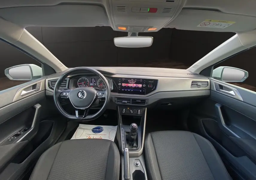 Vue intérieure avant de la Volkswagen Polo 1.0 80ch Lounge Business 2020, volant multifonction noir et console centrale avec boîte manuelle.