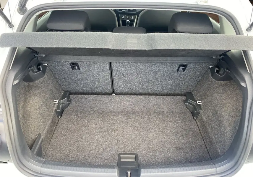 Vue intérieure du coffre ouvert d'une Volkswagen Polo blanche 2020, montrant l'espace de chargement et les sièges arrière noirs.