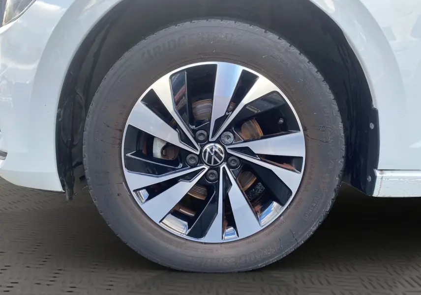 Gros plan sur la roue avant droite d'une Volkswagen Polo blanche avec jante alliage bicolore brillante.