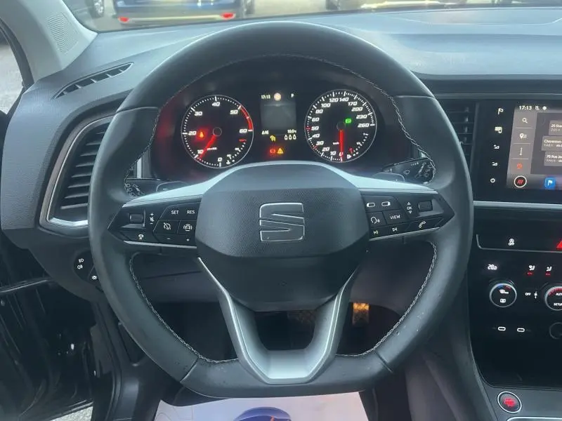 Vue rapprochée du volant cuir multifonction noir du SEAT Ateca 2022 avec tableau de bord et écran tactile visibles.