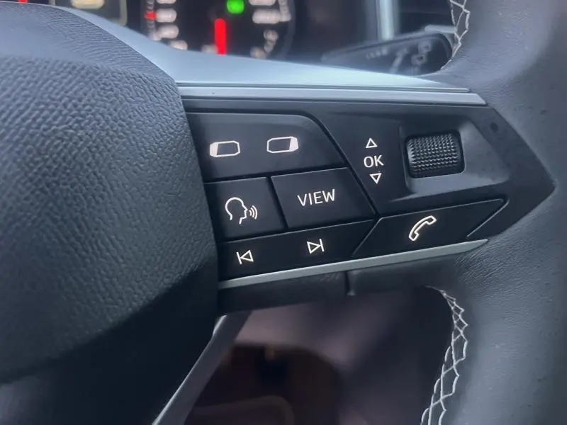 Gros plan sur les commandes multifonctions en noir mat du volant cuir du SEAT Ateca 2022, avec touches rétroéclairées blanches.