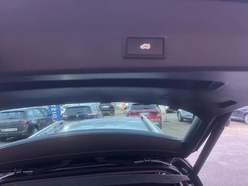 Vue intérieure du hayon ouvert d'un SEAT Ateca noir, montrant le bouton de fermeture électrique et l'arrière du véhicule.