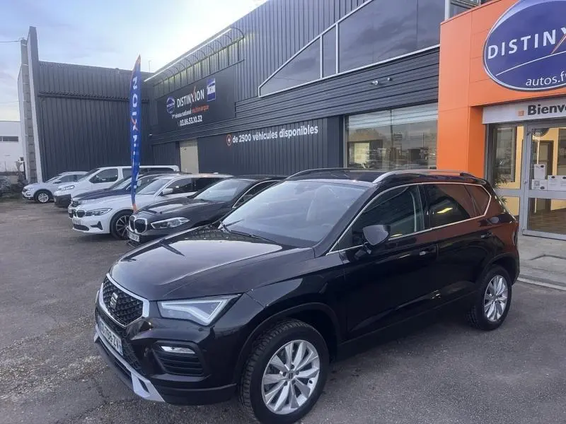 SEAT Ateca noir Magique Métal en 3/4 avant droit, avec jantes alliage et calandre chromée, stationné devant un concessionnaire.