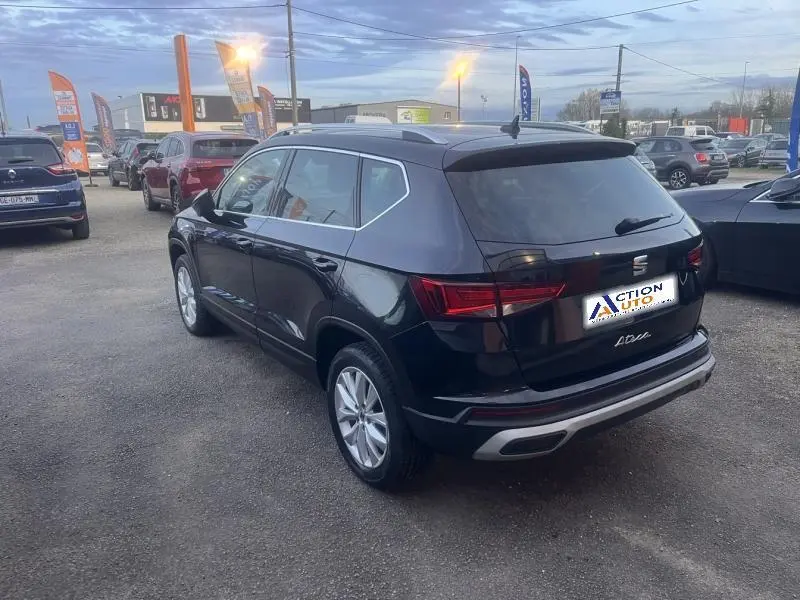 Vue 3/4 arrière droite d'un SEAT Ateca noir métallique, avec vitres arrière surteintées et jantes alliage.
