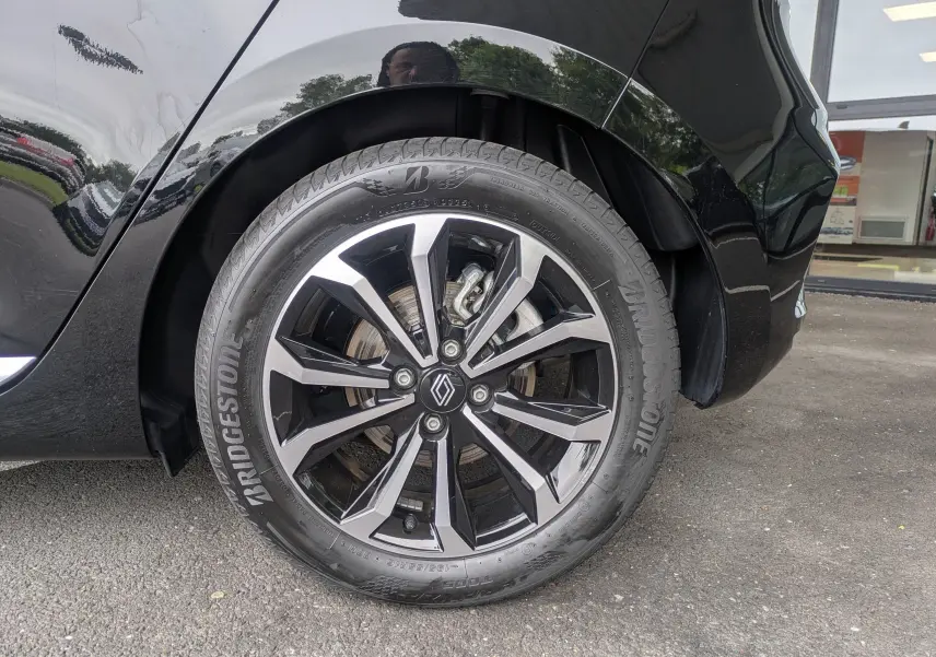 Gros plan sur la roue arrière droite noire étoile métal d'une Renault Clio 2025 avec jante alliage bicolore et pneu Bridgestone.