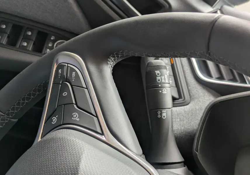 Vue rapprochée du volant cuir noir et des commandes au volant côté gauche dans l’habitacle gris noir d’une Renault Clio 2025.