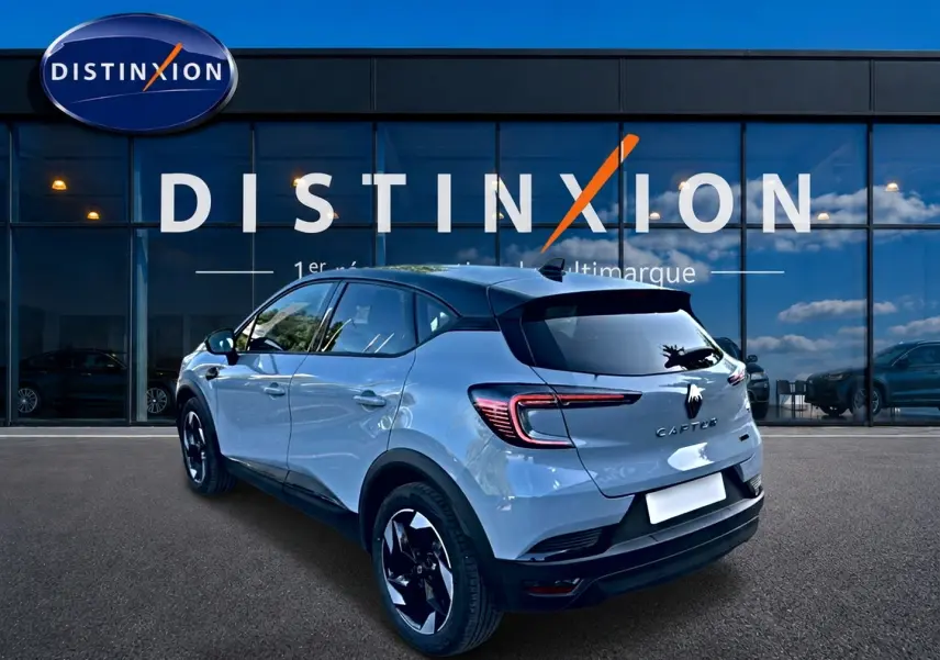 Vue 3/4 arrière droite d'un Renault Captur gris rafale avec toit noir et feux arrière LED, devant une vitrine Distinxion.