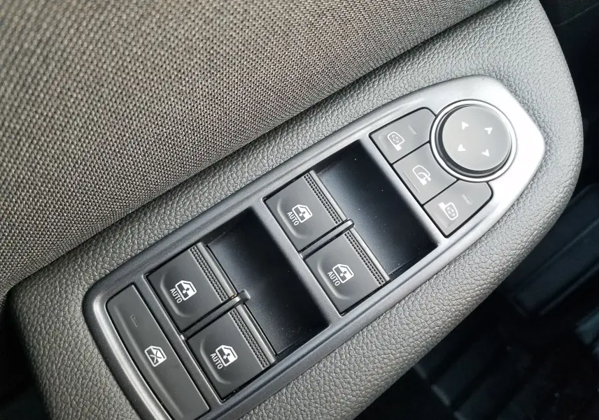 Gros plan sur les commandes de lève-vitres et rétroviseurs sur la porte côté conducteur d'une Renault Clio V gris Rafale.