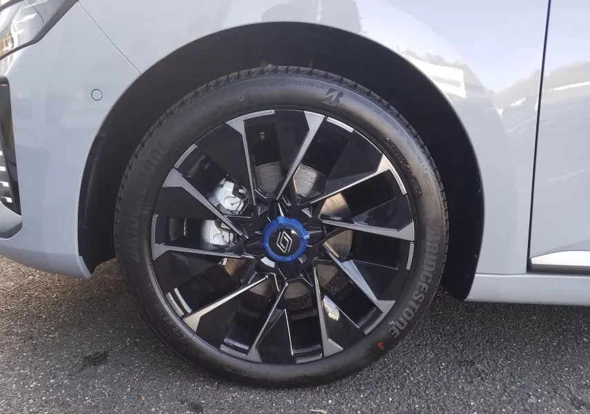 Gros plan sur la roue avant gauche de la Renault Clio V gris Rafale avec jante noire et argentée au design moderne.