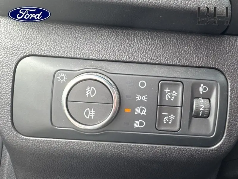 Gros plan sur le panneau de commande des phares et feux antibrouillard du Ford Kuga 2022, intérieur noir texturé.