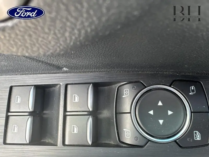 Gros plan sur les commandes des vitres et rétroviseurs côté conducteur du Ford Kuga 2.5 Duratec gris Solar Métallisée.