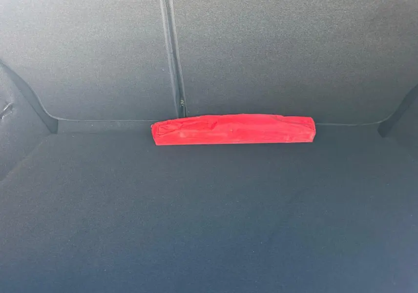 Coffre vide d'une Renault Clio bleu foncé 2023, avec un triangle de signalisation rouge posé à plat.