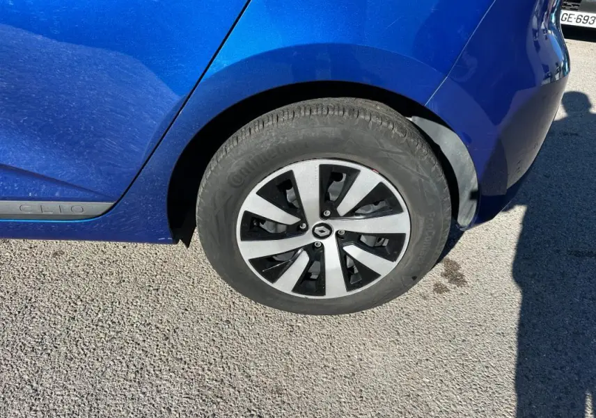 Gros plan sur la roue arrière droite d'une Renault Clio bleu foncé 2023 avec jante alliage au design moderne.