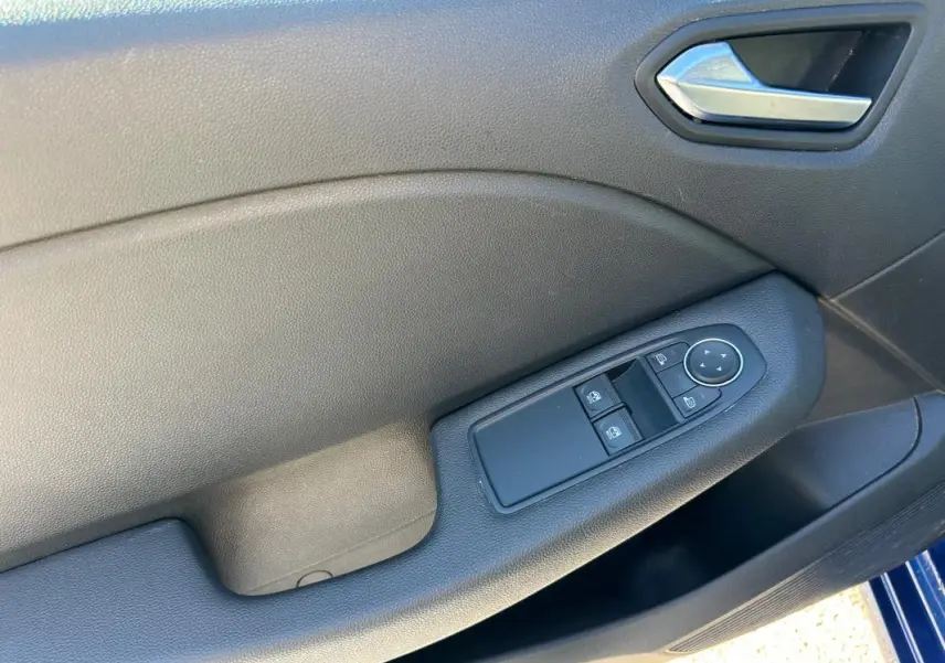Panneau de porte côté conducteur de Renault Clio bleu foncé 2023 avec commandes électriques des vitres et rétroviseurs.