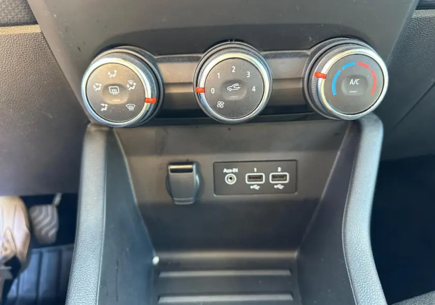 Gros plan sur les commandes de climatisation manuelle et les ports USB d'une Renault Clio V TCe 90 bleu foncé de 2023.