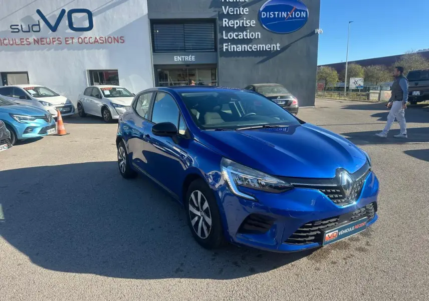 Renault Clio V TCe 90 Equilibre bleu foncé vue 3/4 avant droit sur parking devant concessionnaire