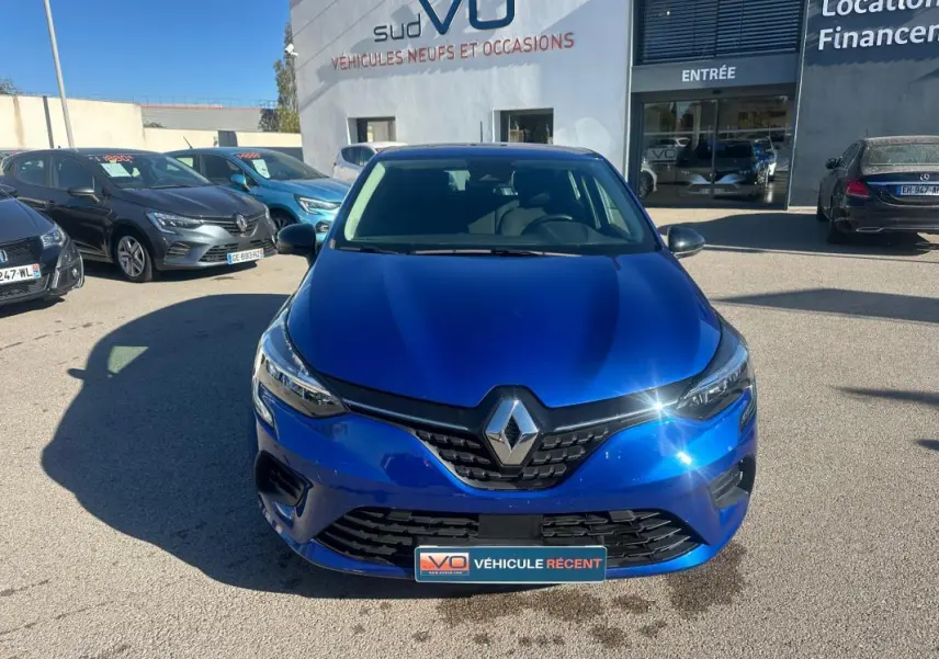 Renault Clio V TCe 90 bleu foncé vue de face, avec calandre noire et logo Renault brillant au soleil.