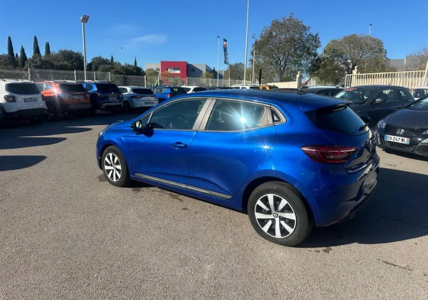 Renault Clio V TCe 90 bleu foncé vue de trois quarts arrière droit sur parking ensoleillé.