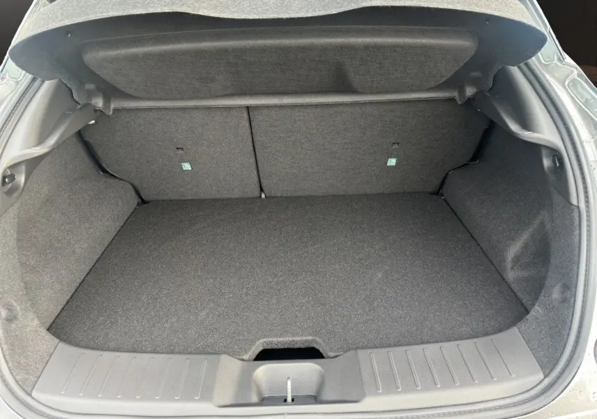Coffre ouvert vu de l’arrière d’un Nissan Juke 1.6 Hybrid 2025 gris squale, espace de chargement vide et propre.
