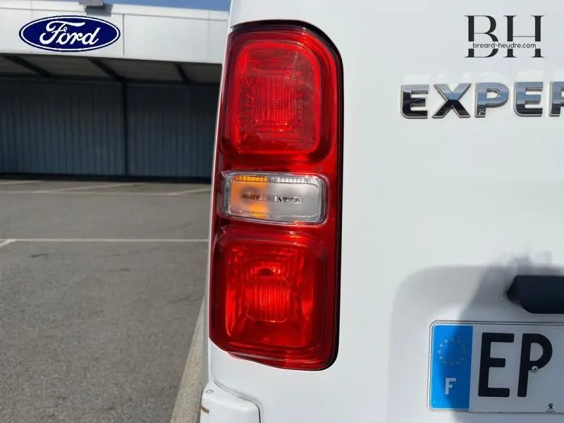 Gros plan sur le feu arrière gauche blanc banquise du Peugeot Expert Fourgon 2017 avec partie du logo et plaque visible.