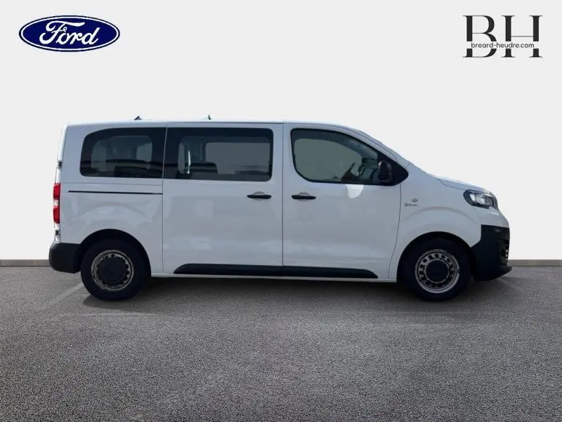 Vue de profil côté droit d'un Peugeot Expert Fourgon blanc banquise avec vitres latérales teintées et portes coulissantes.