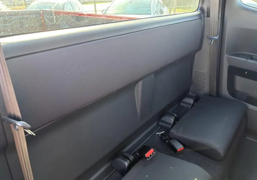 Vue intérieure arrière côté droit du pick-up Isuzu D-MAX 2026, sièges arrière rabattus en tissu noir.