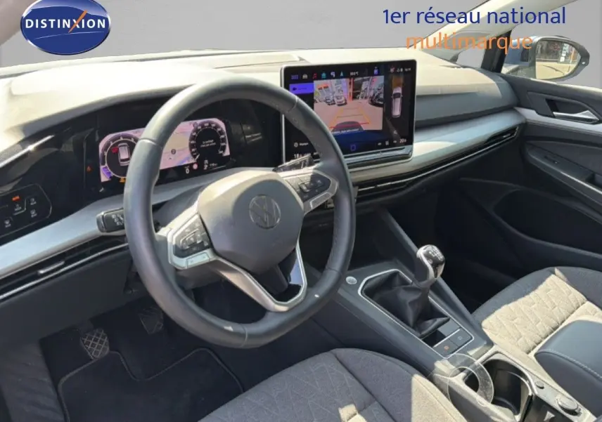 Vue intérieure côté conducteur de la Volkswagen Golf SW 1.5 TSI 2026, avec tableau de bord numérique et levier de vitesse manuel.