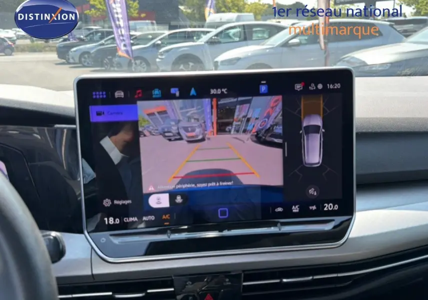 Vue intérieure du tableau de bord de la Volkswagen Golf SW 2026 avec écran tactile affichant la caméra de recul et l'aide au stationnement.
