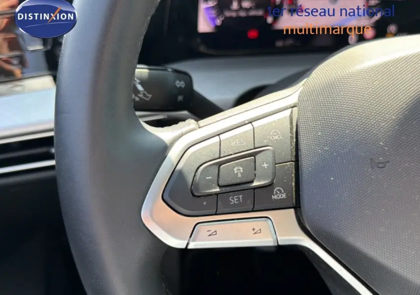 Gros plan sur les commandes au volant à gauche d’une Volkswagen Golf SW 2026, intérieur gris noir.