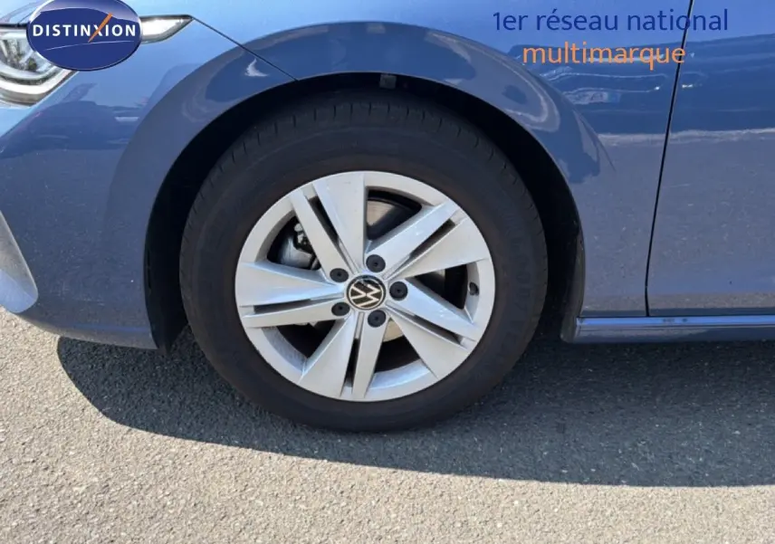 Gros plan sur la roue avant gauche d'une Volkswagen Golf SW bleu Anemone, avec jante alliage à cinq branches.