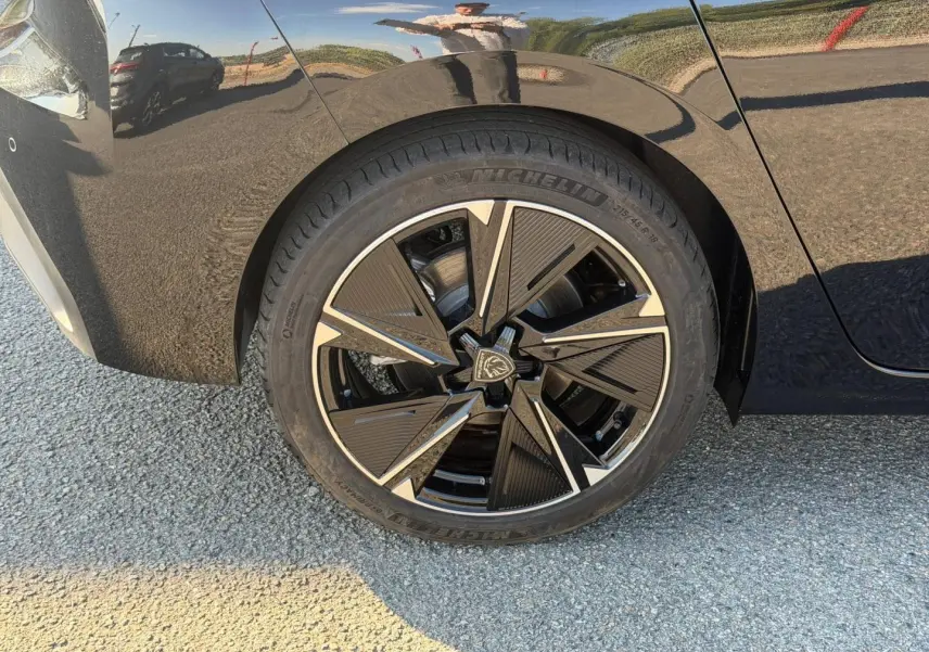Gros plan sur la roue arrière droite noire Perla Nera d'une Peugeot e-308 2025 avec jante alu au design moderne.