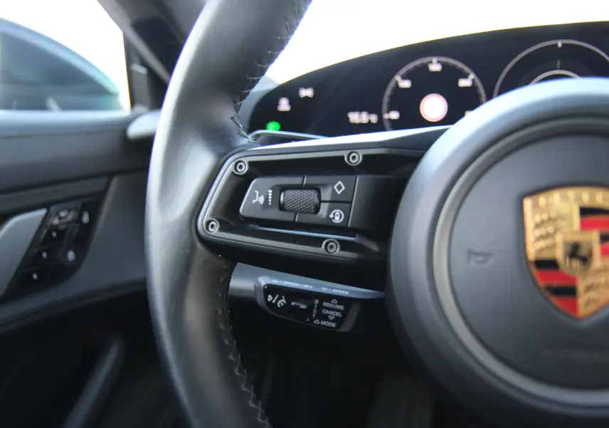 Gros plan sur le volant cuir noir du Porsche Taycan Turbo 2020 avec commandes intégrées et tableau de bord numérique.