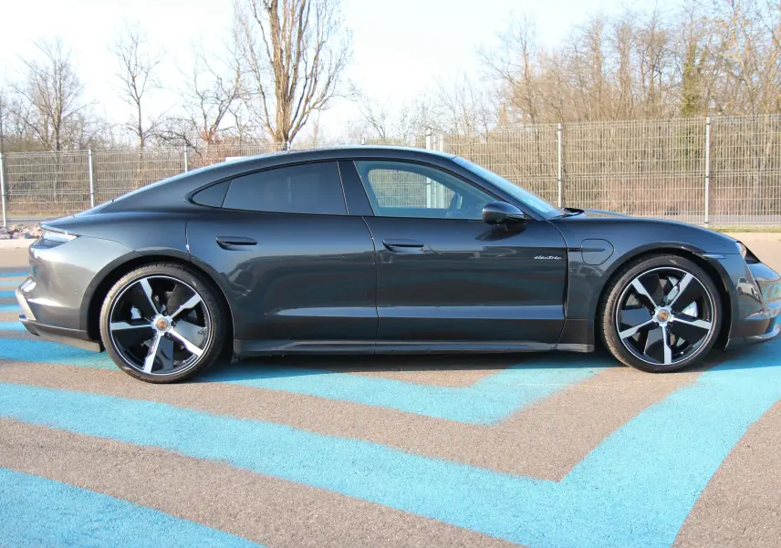Vue latérale droite d'une Porsche Taycan Turbo gris anthracite avec jantes exclusives 21 pouces et toit panoramique.