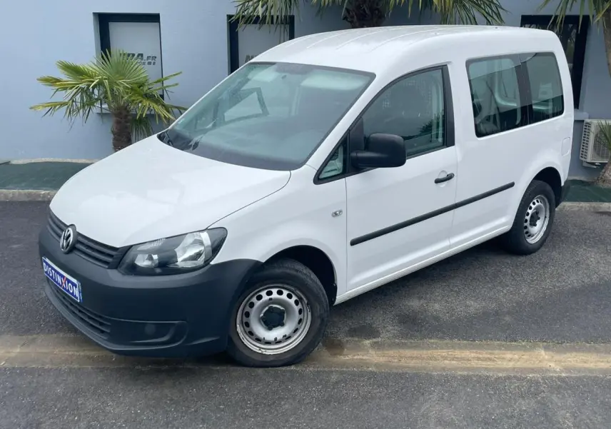 Volkswagen Caddy blanc Candy vu en 3/4 avant droit avec pare-chocs noirs et jantes acier simples.