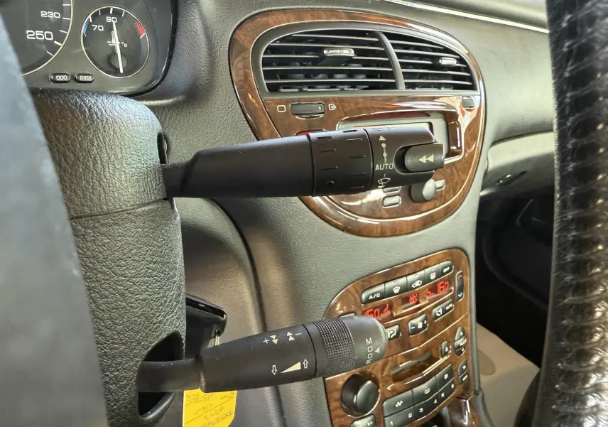 Gros plan sur la console centrale et les commandes de la Peugeot 607 gris, avec finition bois et affichage digital rouge.