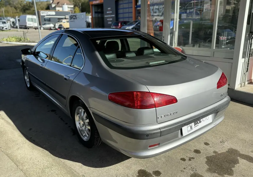 Peugeot 607 gris vue 3/4 arrière côté gauche, avec feux rouges et jantes alliage en extérieur.