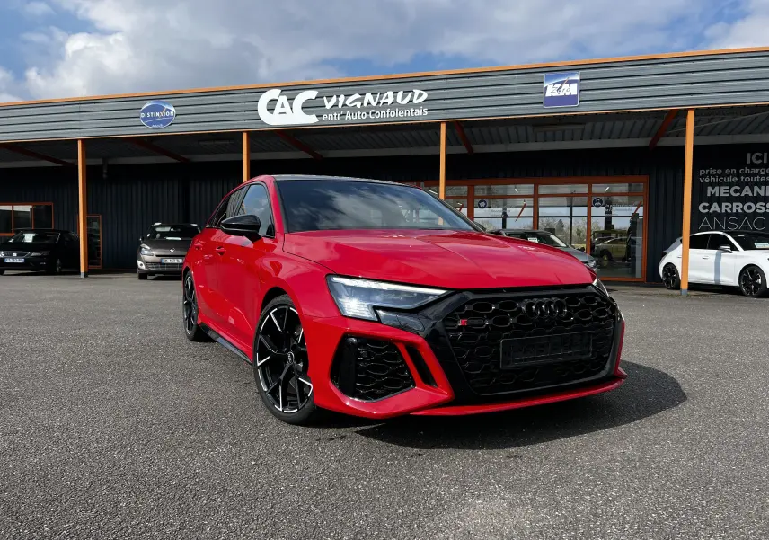 Audi RS3 Sportback rouge vue 3/4 avant droit, avec calandre noire et jantes noires distinctives.