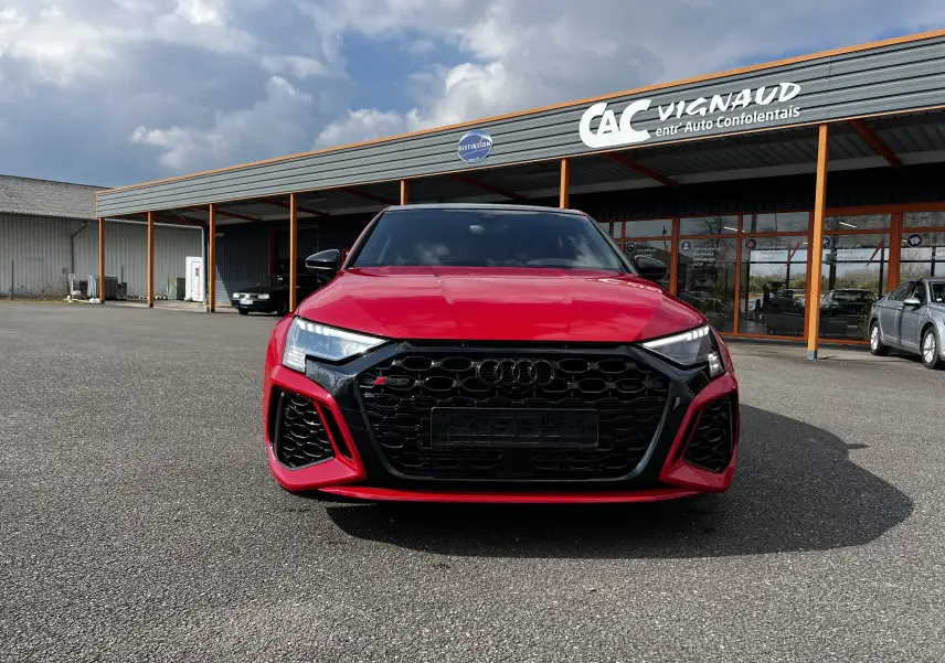 Vue de face d'une Audi RS3 Sportback rouge 2022 avec calandre noire et phares LED distinctifs.