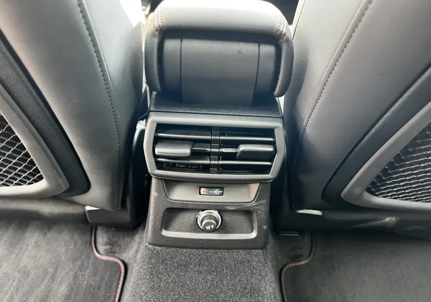 Vue rapprochée des aérateurs arrière et prise 12V entre les sièges noirs de l'Audi RS3 Sportback rouge 2022.