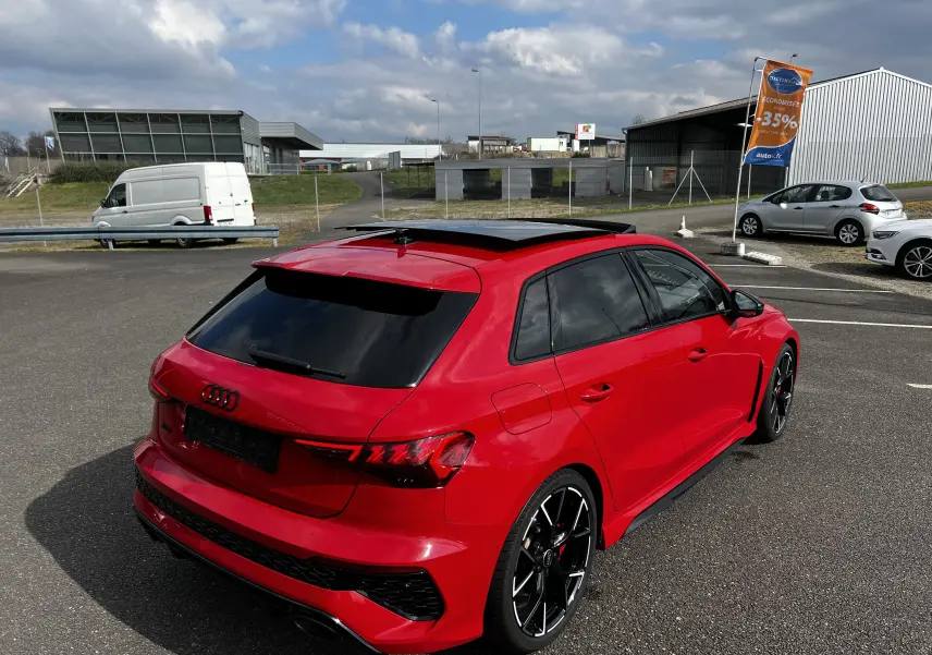 Audi RS3 Sportback rouge vue 3/4 arrière droit avec jantes noires et toit ouvrant panoramique.