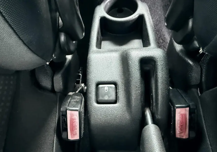 Vue rapprochée de la console centrale noire entre les sièges avant d’une Peugeot 206+ 2011.