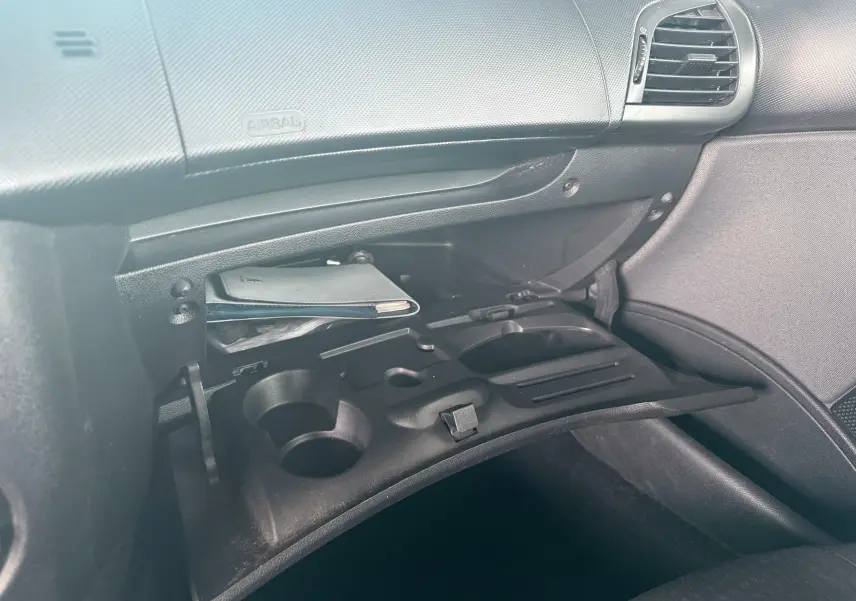 Intérieur de la Peugeot 206+ 2011, vue du vide-poche passager ouvert avec documents à l’intérieur.