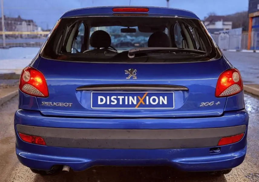 Vue arrière d'une Peugeot 206+ bleue avec feux allumés et plaque d'immatriculation Distinxion.