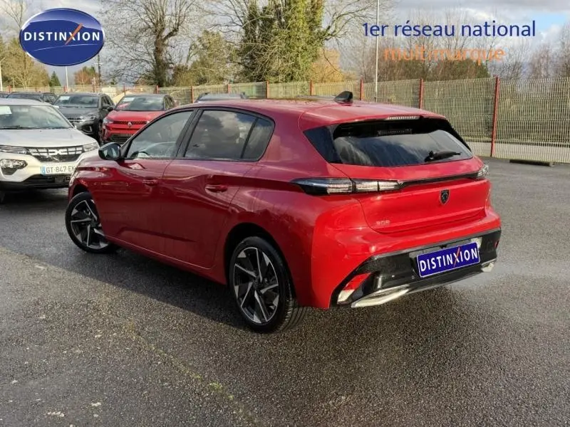 Vue 3/4 arrière droite d'une Peugeot 308 2024 Rouge Elixir avec feux arrière effilés et jantes alliage noires.