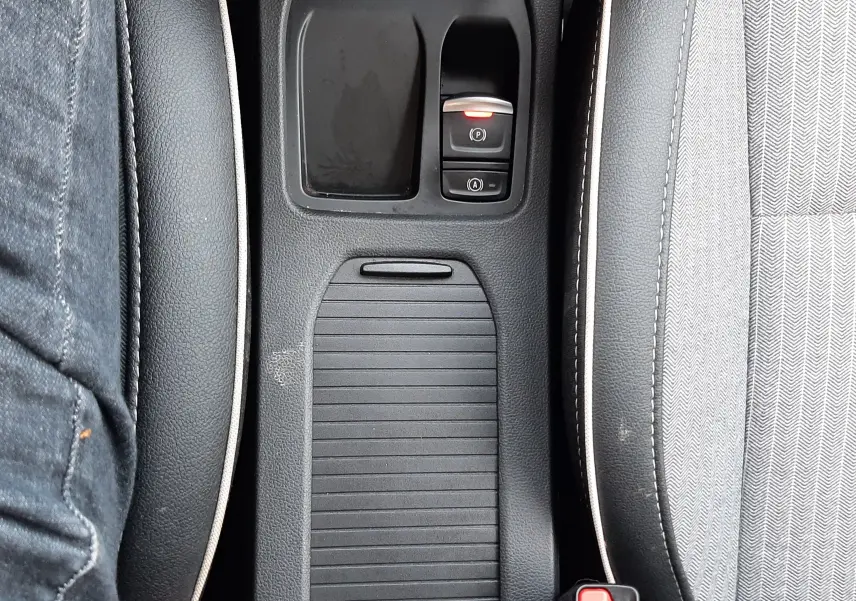 Vue plongeante sur la console centrale noire de la Renault Clio V, avec commandes de frein à main électronique et bouton start/stop.